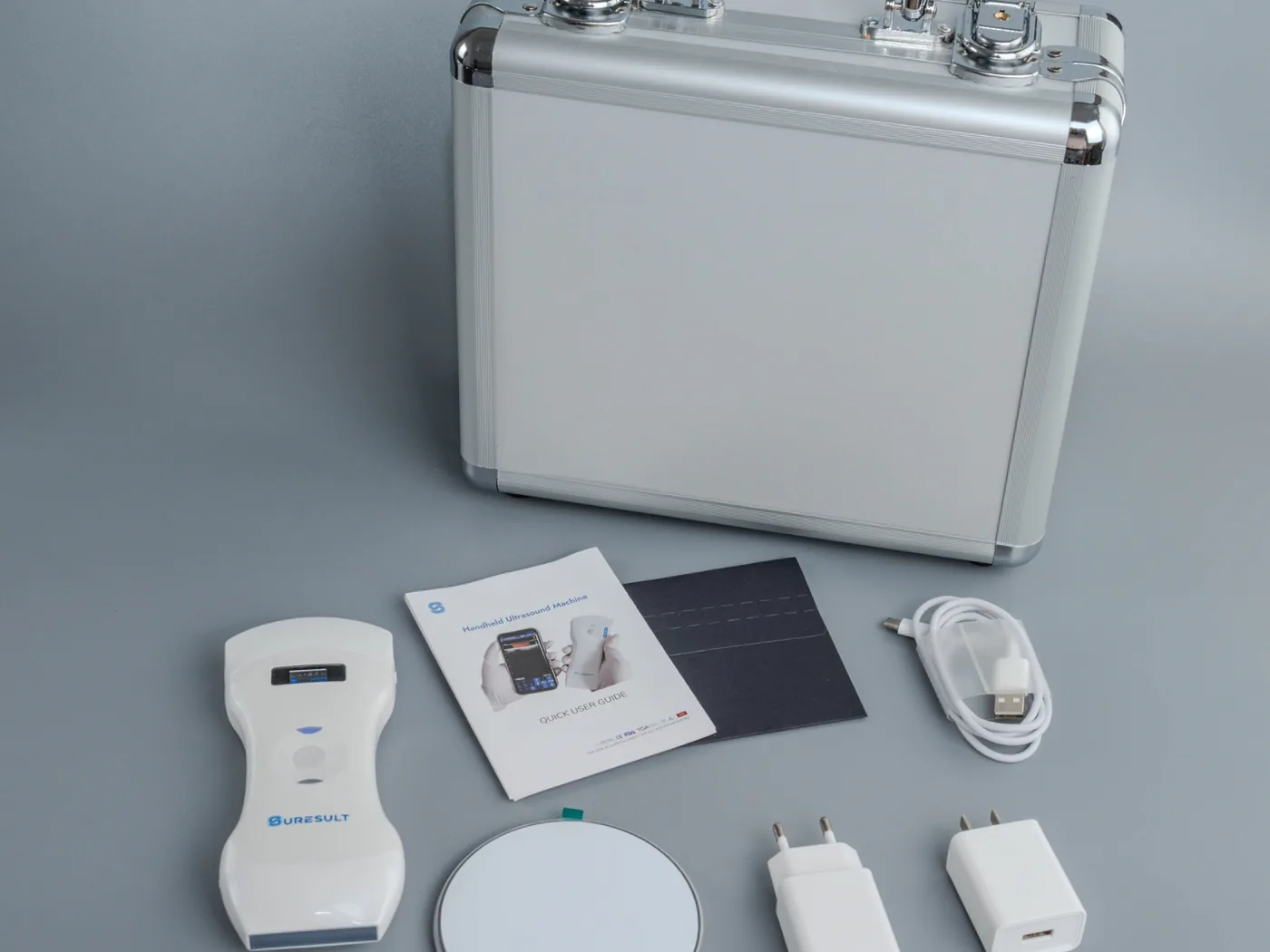 Een uitgestalde Suresult-set: aluminium koffer, probe, beknopte handleiding, draadloos oplaadstation, stekkers en kabel