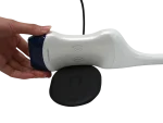 Suresult D2LT dual-head probe held in hand beside its charging pad